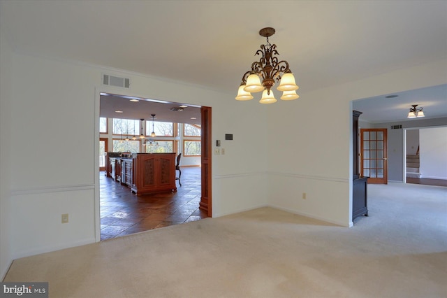 carpeted spare room with a notable chandelier and crown molding