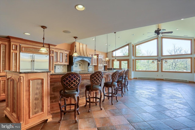 kitchen with lofted ceiling, a kitchen breakfast bar, built in refrigerator, decorative light fixtures, and ceiling fan