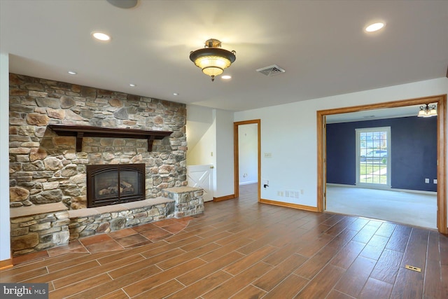 unfurnished living room featuring a stone fireplace and hardwood / wood-style floors