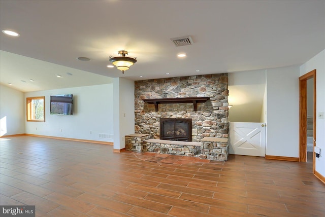 unfurnished living room featuring a stone fireplace and wood-type flooring