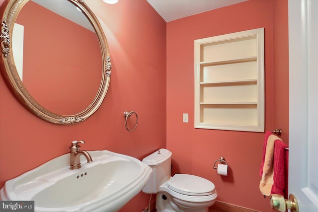 bathroom featuring sink, built in shelves, and toilet