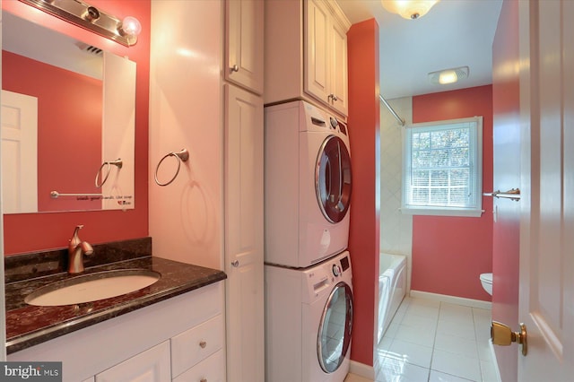 washroom with sink, stacked washer and dryer, and light tile patterned floors