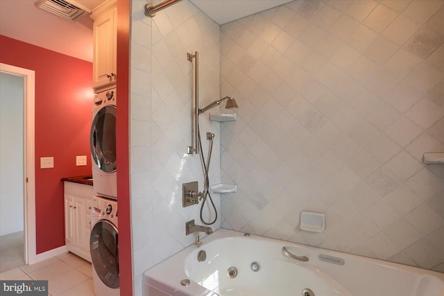 bathroom featuring vanity, stacked washer / dryer, tile patterned flooring, and tiled shower / bath