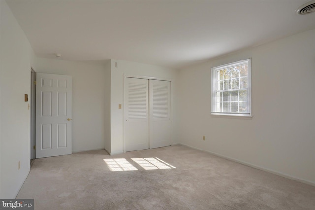 unfurnished bedroom with a closet and light colored carpet