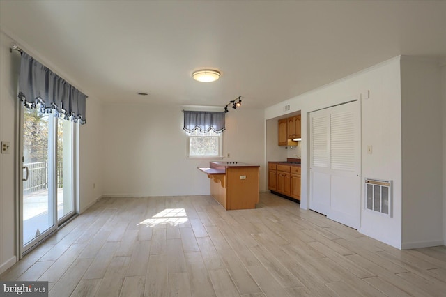 kitchen featuring heating unit, light wood-type flooring, a kitchen island, and a kitchen breakfast bar