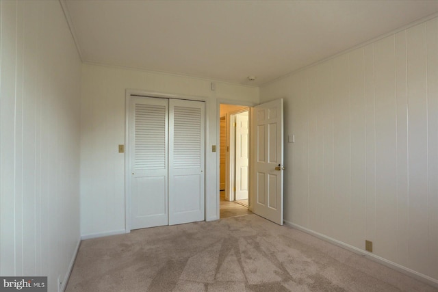 unfurnished bedroom with a closet, light colored carpet, and crown molding