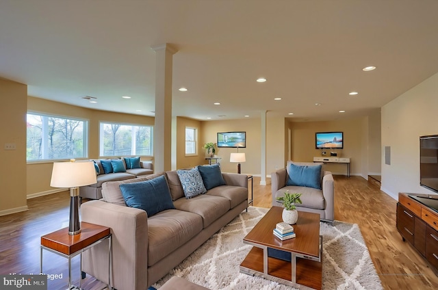 living room with ornate columns and light hardwood / wood-style floors