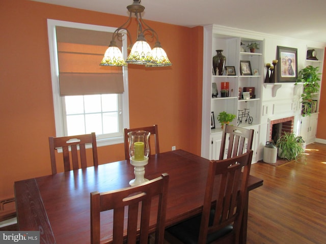 dining room with a notable chandelier, hardwood / wood-style flooring, and a brick fireplace