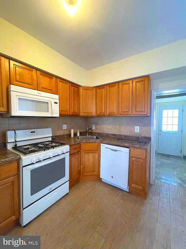 kitchen with white appliances, decorative backsplash, light hardwood / wood-style flooring, and sink