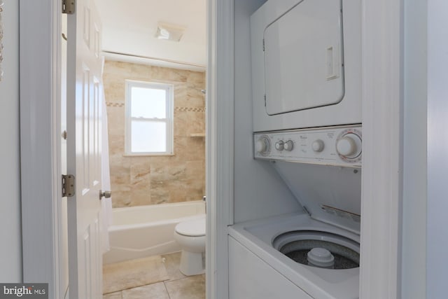 clothes washing area featuring light tile patterned floors and stacked washer / dryer