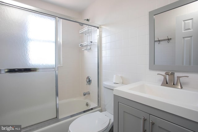 full bathroom featuring vanity, backsplash, bath / shower combo with glass door, toilet, and tile walls