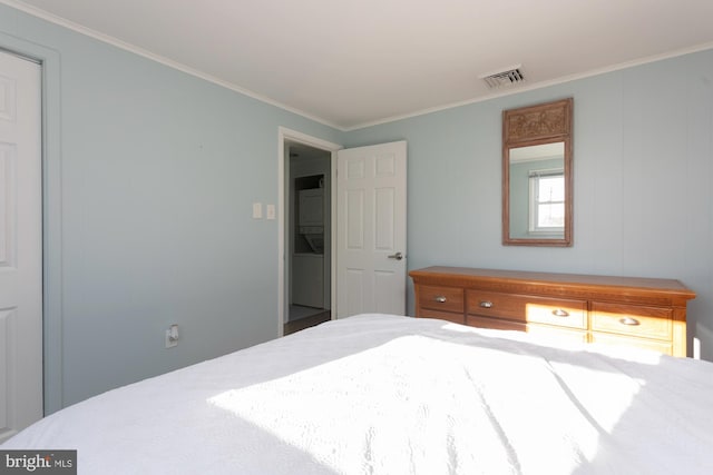 bedroom with stacked washing maching and dryer and ornamental molding