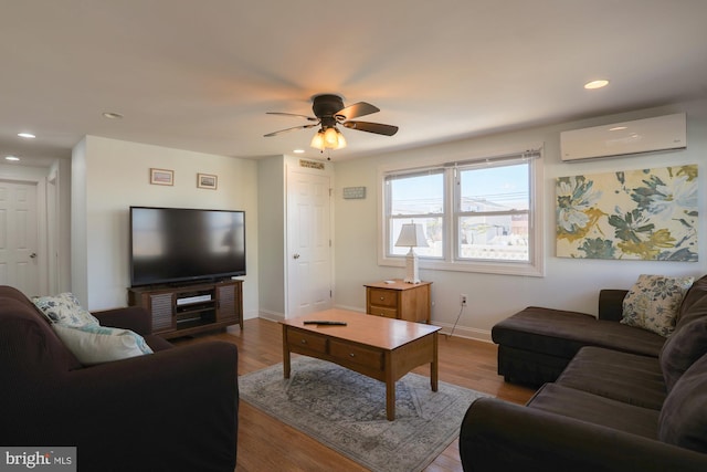 living room with ceiling fan, light hardwood / wood-style flooring, and a wall mounted AC