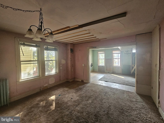 empty room featuring radiator heating unit, a chandelier, and light colored carpet