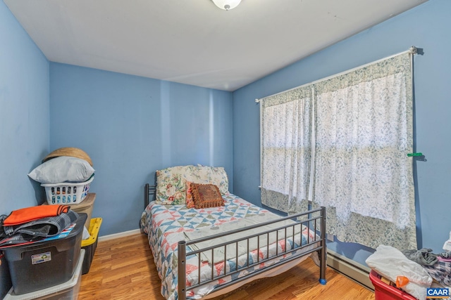 bedroom with hardwood / wood-style flooring and baseboard heating