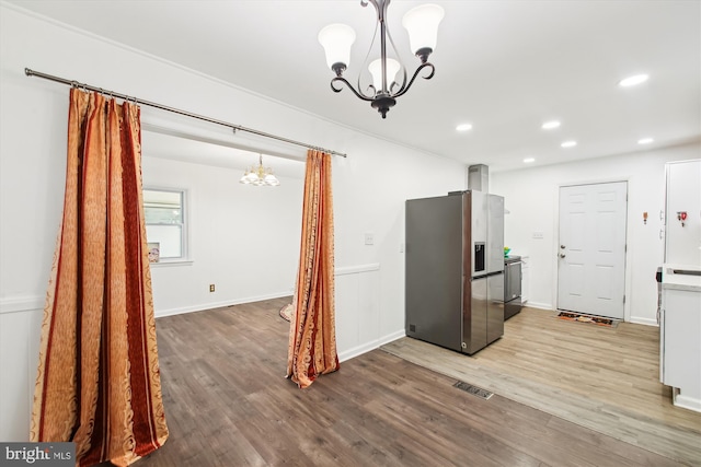 kitchen with a notable chandelier, wood-type flooring, pendant lighting, and stainless steel fridge with ice dispenser