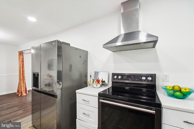 kitchen featuring hardwood / wood-style floors, appliances with stainless steel finishes, wall chimney range hood, and white cabinetry