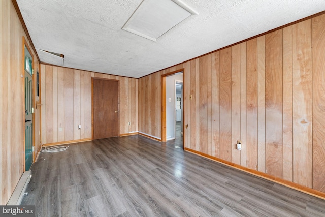 empty room featuring wood walls, hardwood / wood-style flooring, and a textured ceiling