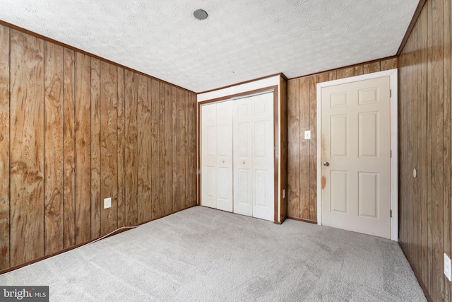 unfurnished bedroom featuring a closet, wooden walls, and light colored carpet