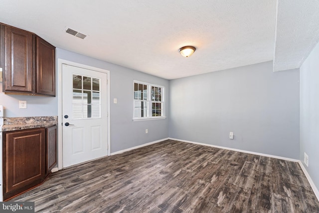 unfurnished dining area featuring a textured ceiling and dark hardwood / wood-style floors