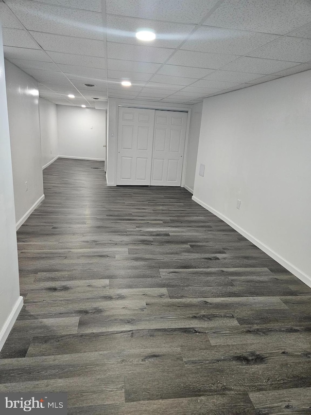 basement featuring dark wood-type flooring and a drop ceiling