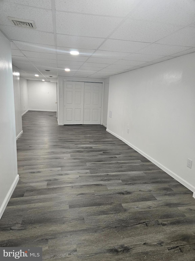 basement featuring dark wood-type flooring and a paneled ceiling