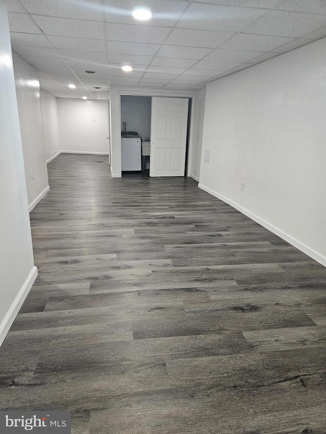 basement with a drop ceiling, washer / clothes dryer, and dark wood-type flooring