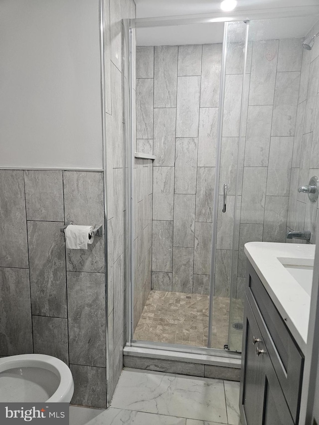 bathroom with a shower with door, vanity, toilet, and tile walls