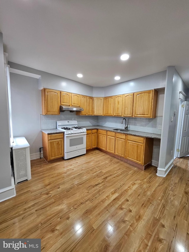 kitchen with sink, light hardwood / wood-style floors, white range with gas cooktop, and radiator heating unit