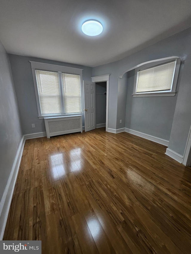 unfurnished bedroom featuring wood-type flooring and radiator heating unit