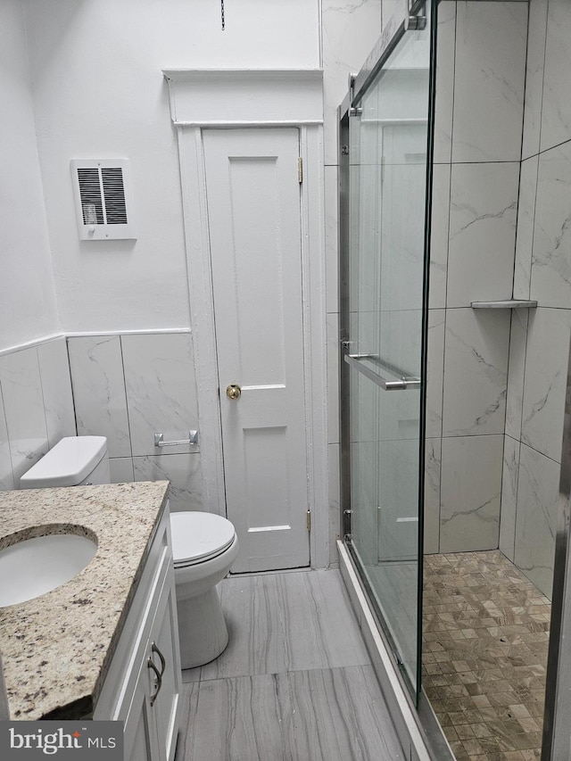 bathroom with toilet, walk in shower, vanity, and tile walls