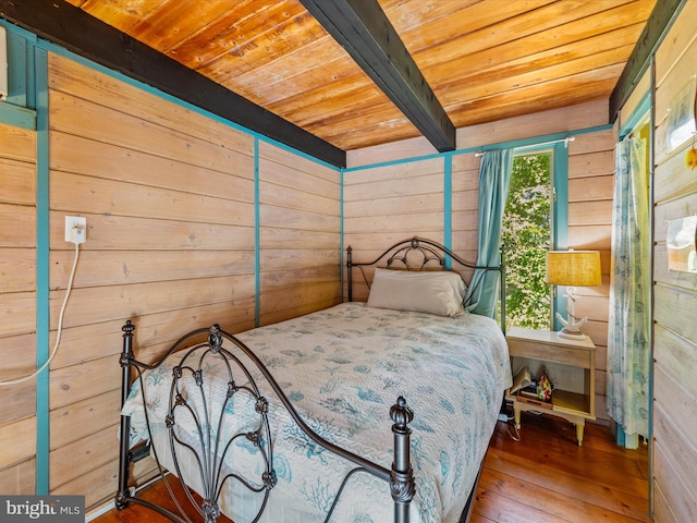 bedroom featuring hardwood / wood-style floors, beamed ceiling, wooden ceiling, and wooden walls