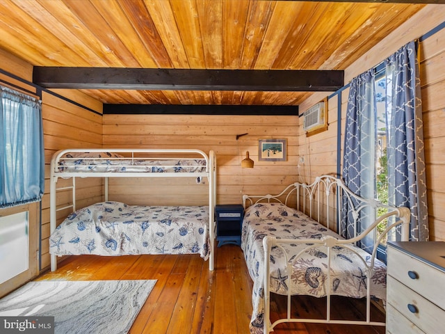 bedroom with beam ceiling, hardwood / wood-style flooring, multiple windows, and wood walls