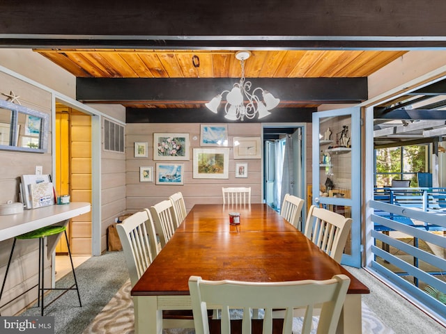 carpeted dining area featuring beamed ceiling, a chandelier, and wooden ceiling