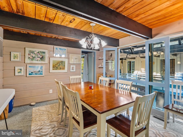 dining space featuring beam ceiling, a chandelier, light carpet, and wooden ceiling