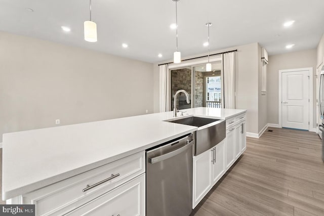 kitchen featuring light hardwood / wood-style flooring, sink, decorative light fixtures, stainless steel dishwasher, and white cabinets