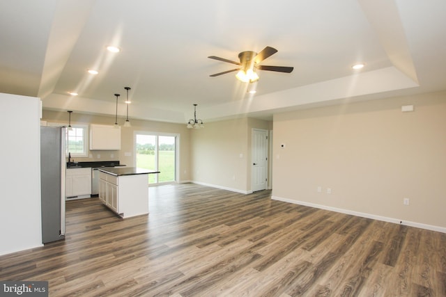 kitchen with a center island, white cabinetry, stainless steel appliances, pendant lighting, and dark hardwood / wood-style floors