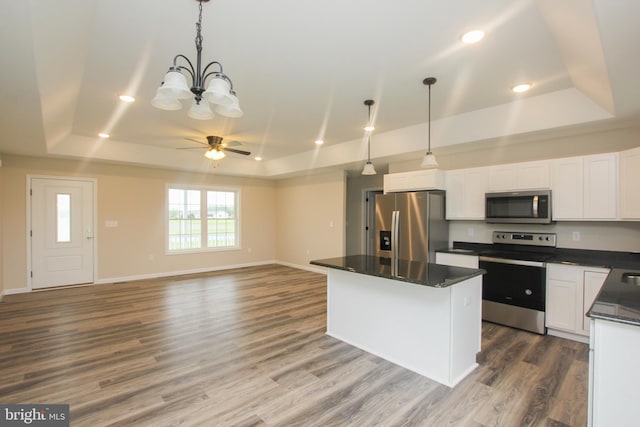 kitchen with appliances with stainless steel finishes, dark hardwood / wood-style floors, pendant lighting, and a raised ceiling