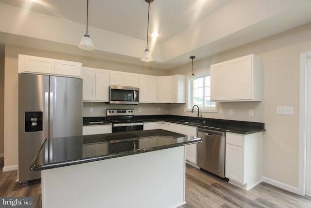 kitchen featuring appliances with stainless steel finishes, sink, hanging light fixtures, dark stone counters, and white cabinets