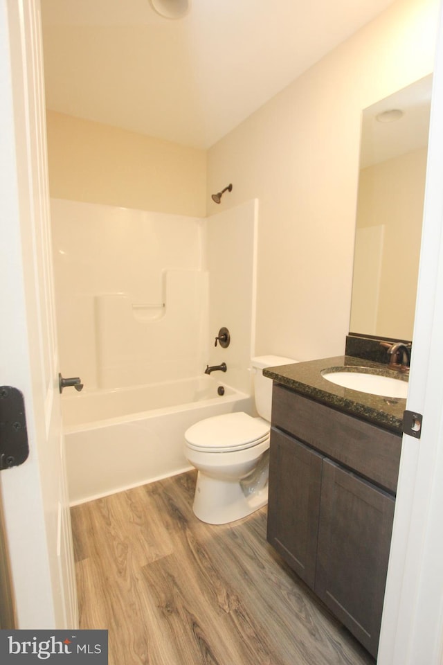 full bathroom with toilet, vanity, wood-type flooring, and washtub / shower combination