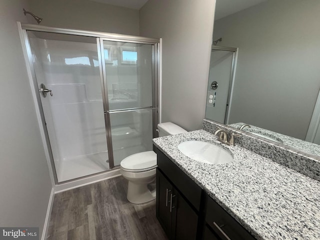 bathroom featuring vanity, hardwood / wood-style floors, a shower with shower door, and toilet