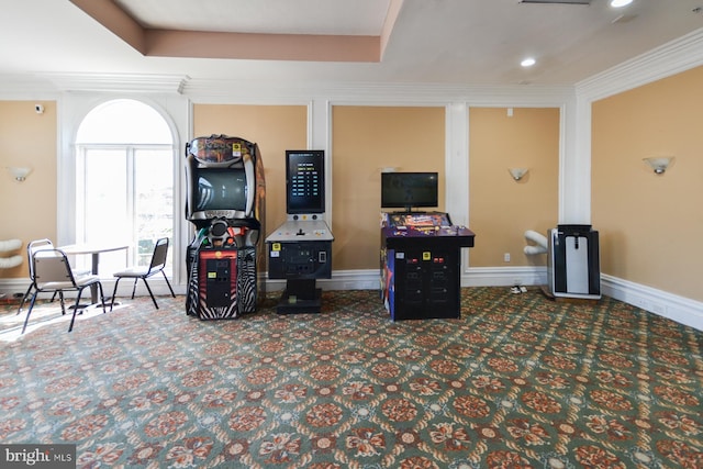 rec room with dark colored carpet, a raised ceiling, and ornamental molding