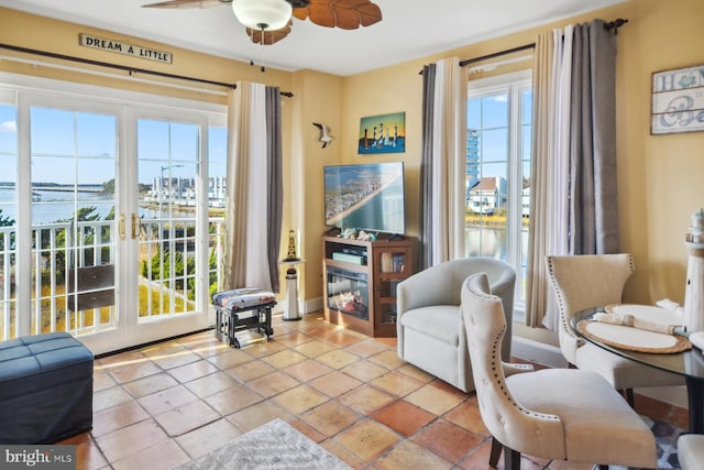 living area with a water view and ceiling fan