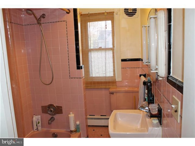 bathroom with tiled shower / bath, tile walls, sink, and a baseboard heating unit