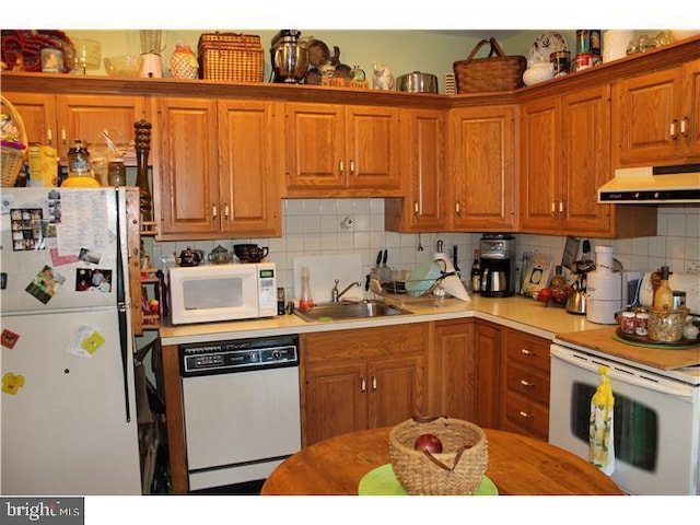 kitchen with sink, backsplash, and white appliances