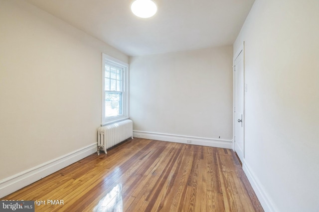 empty room with radiator heating unit and hardwood / wood-style flooring