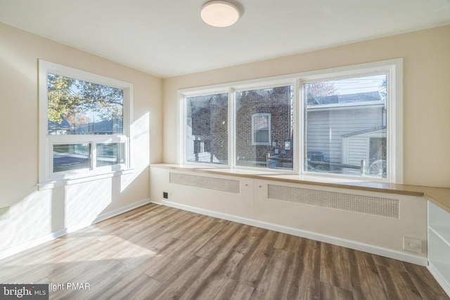 spare room featuring wood finished floors, a healthy amount of sunlight, and baseboards