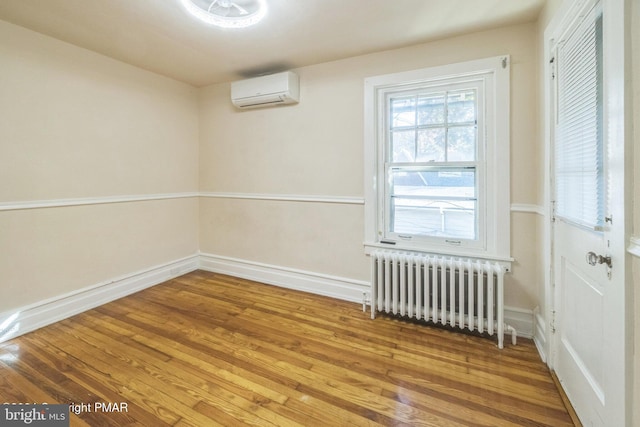 spare room featuring wood-type flooring, radiator, and an AC wall unit