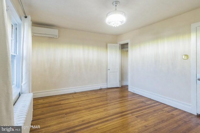 empty room with a wall mounted AC, dark wood-type flooring, and plenty of natural light