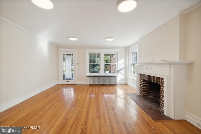 unfurnished living room with ornamental molding, radiator heating unit, hardwood / wood-style flooring, and a brick fireplace